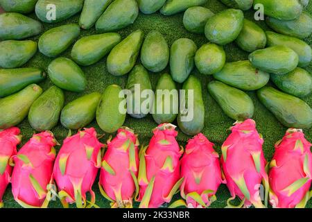Stapel von Pitaya oder Drachenfrucht, großer Haufen rosa Drachenfrucht und grüne Bio-Avocado auf dem Markt, auf dem traditionellen Markt, Kopierraum. Stockfoto