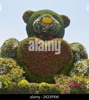 Dubai, VAE. 01. Juni 2022: Ein großer Teddybär mit einem Herz aus roten Blumen im Dubai Miracle Garden. Stockfoto