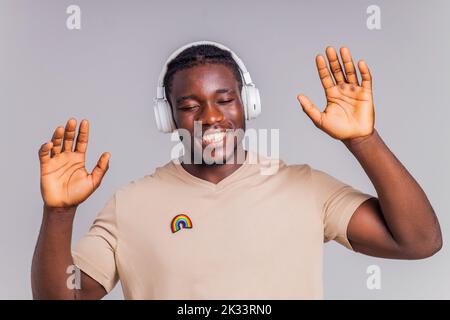 mexikanischer Mann mit weißem Kopfhörer, der Musik in beigefarbenem T-Shirt hört Stockfoto