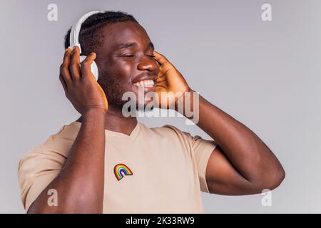 mexikanischer Mann mit weißem Kopfhörer, der Musik in beigefarbenem T-Shirt hört Stockfoto