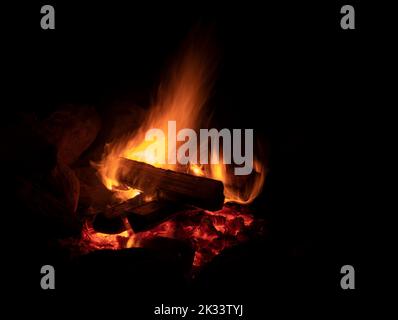 Nächtliches Lagerfeuer, das hell brennt, mit Felsen herum Stockfoto