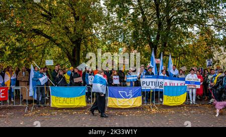 Den Haag, Niederlande. 24. September 2022. Man sieht eine Frau, die vor den Demonstranten läuft, während sie die Flagge der Freien Russischen Föderation trägt. Vor der russischen Botschaft in Den Haag organisierte die russische Gemeinschaft in den Niederlanden einen Protest gegen das Dekret von Präsident Wladimir Putin, teilweise Reservisten in Russland zu mobilisieren, und gegen den Krieg in der Ukraine. Trotz der harten Gesetze Russlands gegen die Kritik am Militär und am Krieg fanden im ganzen Land Proteste statt. Mehr als 1.300 Russen wurden bei Antikriegsdemonstrationen in 38 Städten verhaftet. Kredit: SOPA Images Limited/Alamy Live Nachrichten Stockfoto