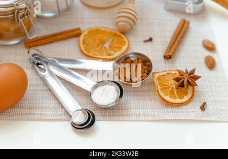 Messlöffel mit Backpulver, Mehl und Kakaopulver auf einem weißen Tisch mit Küchenutensilien Stockfoto