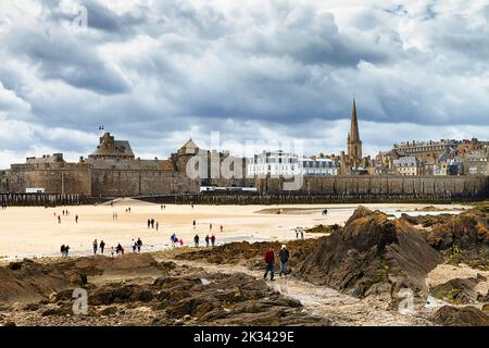 Blick auf die Stadtmauer und die Kathedrale vom Fort National, Spaziergänger am Strand, Saint-Malo, Emerald Coast, Cote d'Emeraude, Bretagne, Frankreich Stockfoto