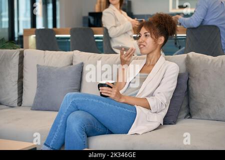 Frau, die im Co-Working-Bereich mit dem Handy spricht Stockfoto
