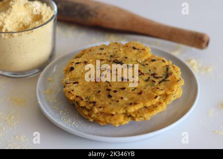 Makki KI roti oder Mais roti. Ein indisches, flaches ungesäuertes Brot aus Maismehl. Schuss auf weißem Hintergrund zusammen mit einer Tasse Maismehl Stockfoto