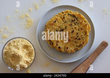 Makki KI roti oder Mais roti. Ein indisches, flaches ungesäuertes Brot aus Maismehl. Schuss auf weißem Hintergrund zusammen mit einer Tasse Maismehl Stockfoto