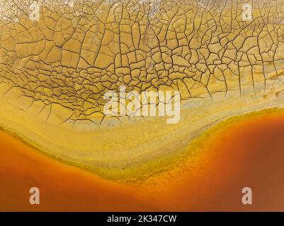 Gesprungene Erde am Ufer des Rio Tinto (Red River) mit seinem tiefen rötlichen Farbton aufgrund oxidierter Eisenminerale im Wasser, Luftaufnahme, Drohnenschuss Stockfoto