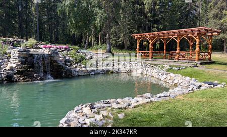 Der hölzerne Pavillon mit einem Teich, umgeben von grüner Vegetation. Cascade Garden in Banff, Alberta, Kanada. Stockfoto