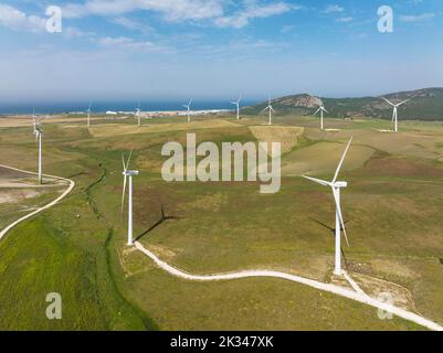 Windmühlen auf einem Windpark, in der Ferne Zahara de los Atunes und die Küste des Atlantischen Ozeans, Luftaufnahme, Drohnenaufnahme, Provinz Cádiz Stockfoto