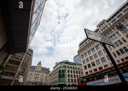 Schilder für die Docklands, Westminster und Tower Bridge mit einem ikonischen Doppeldeckerbus und einem Flugzeug, das über den Himmel fliegt. London, 26. 2013. Juni, Stockfoto