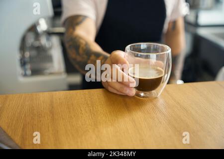 Professioneller Mitarbeiter im Coffee Shop, der frischen Espresso präsentiert Stockfoto