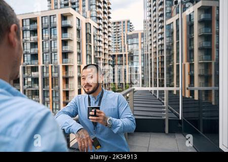 Büroangestellter, der während der Kaffeepause mit seinem Kollegen ins Gespräch kommt Stockfoto