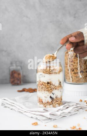 Granola und Joghurt-Parfait in einer Dose geformtes Glas, Hafer und Nüsse Parfait, gerösteter Honig Müsli mit Schichten von Joghurt in Dose Glas Tasse Stockfoto