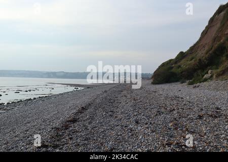 Die Wellen brechen sanft zum Kiesstrand von Axmouth in Devon auf. Stockfoto