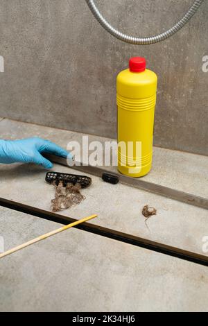 Weibliche Hand in einem blauen Handschuh entfernt die Reste der Haare. Stockfoto