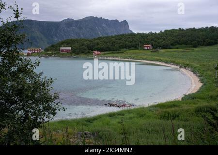 Wunderschöne Landschaften in Norwegen. Nordland. Wunderschöne Landschaft einer Küste vom Elgsnes Strand. Geripptes Meer an einem bewölkten Sommertag. Traditionelles rotes Hou Stockfoto
