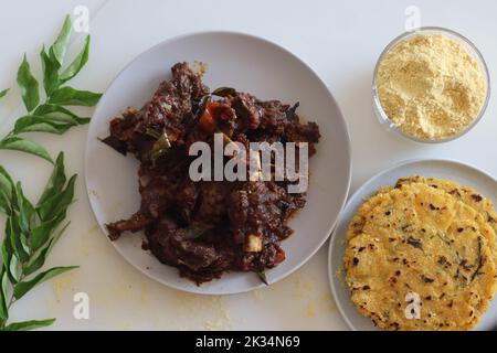 Hammelbraten serviert mit Makki KI roti oder Maisroti. Würziger Hammelbraten im Kerala-Stil, serviert mit indischem, ungesäuertem Fladenbrot aus C. Stockfoto