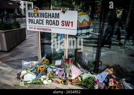 Florale Tribute an die Königin umschließen ein Straßenschild in der Buckingham Palace Road Stockfoto