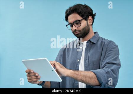 Junger arabischer Mann mit digitalen Tablet isoliert auf blauem Hintergrund. Stockfoto