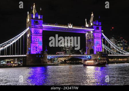 London, Großbritannien, 24.. September 2022. Die Flottille erreicht die Tower Bridge, die als Tribut an die Königin in Purpur beleuchtet ist. Reflections, eine nächtliche Flottille auf der Themse in London, markiert den Tod Ihrer Majestät der Königin und den Beitritt von König Karl III. Die beleuchtete Flottille, die Teil der Totally Thames ist, fährt von der Chelsea Bridge zur Tower Bridge, wobei das Herzstück der Queen's Row Barge Gloriana ist. Kredit: Imageplotter/Alamy Live Nachrichten Stockfoto