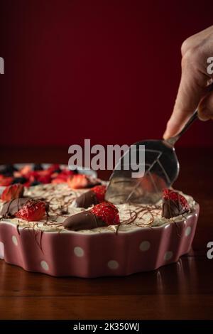 Eine vertikale Aufnahme eines leckeren Käsekuchen mit verschiedenen Beerensorten auf einer Holzfläche Stockfoto
