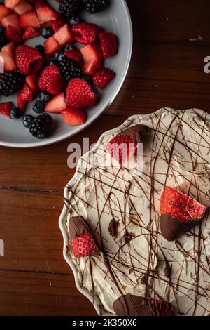 Eine vertikale Aufnahme eines leckeren Käsekuchen mit verschiedenen Beerensorten auf einer Holzfläche Stockfoto