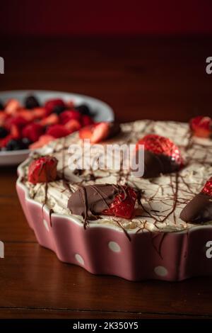 Eine vertikale Aufnahme eines leckeren Käsekuchen mit verschiedenen Beerensorten auf einer Holzfläche Stockfoto