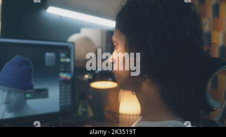 Männlicher junger 3D Designer, der Kleidung mit einem Computer mit professionellem Programm erstellt, während er zu Hause am Tisch sitzt und ferngesteuert an 3D Modellierungen arbeitet Stockfoto