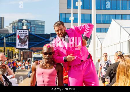 Schwarzer Mann mit rosa Trikot und bärtigem Mann in Anzug auf Stelzen Gay Pride Parade 2022 im Zentrum von birmingham, großbritannien, 24.. september Stockfoto