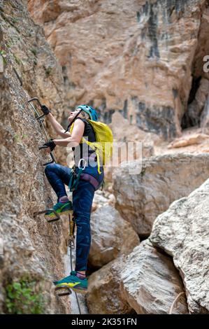Schöne Frau klettert auf Klettersteig Stockfoto