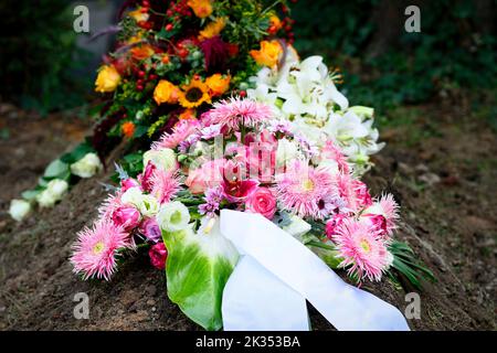 Farbenfrohe Blumenbesetzung auf einem Grab nach der Beerdigung Stockfoto