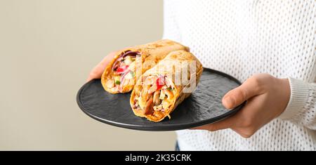 Frau hält Teller mit leckeren Döner Kebabs auf hellem Hintergrund, Nahaufnahme Stockfoto