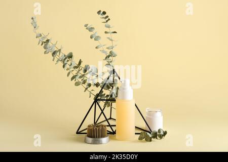 Kosmetikprodukte mit kenzan, Eukalyptuszweigen und Dekor auf beigem Hintergrund Stockfoto