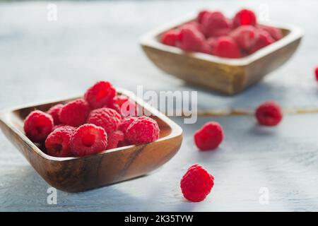 Zwei Holzschalen mit saftig reifen Himbeeren auf weißem Hintergrund. Köstliches gesundes Produkt. Vitamine, Antioxidantien, eine gesunde Lebensweise, Ernährung. Stockfoto