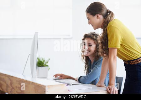 Es sieht alles gut aus. Zwei Kollegen arbeiten gemeinsam am Computer. Stockfoto