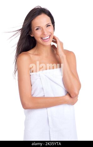 Am glücklichsten nach ihrer morgendlichen Schönheitsroutine. Eine schöne junge Frau, die in einem Handtuch steht und strahlend aussieht. Stockfoto