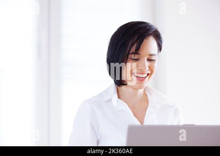 Sie checken ihre E-Mails vor der Arbeit. Eine attraktive junge Frau, die einen Laptop benutzt. Stockfoto