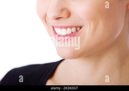 Shes bekam das perfekte Lächeln. Eine unkenntliche Frau lächelte vor weißem Hintergrund. Stockfoto