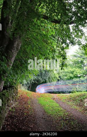 Oben im Westjordanland, in Winster, fährt an einem langweiligen Tag ein Van um die Ecke, wobei die Bremslichter aufleuchten und eine Kurve von rot-weißen Wanderwegen verursachen Stockfoto
