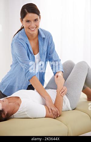 Sie kennt sich um den Körper herum aus. Eine Physiotherapeutin, die an ihrem Patientenarm arbeitet. Stockfoto