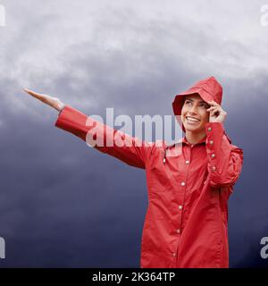 Komm Regen, komm Sonnenschein... ich bin bereit. Eine attraktive junge Frau, die im Regen steht. Stockfoto