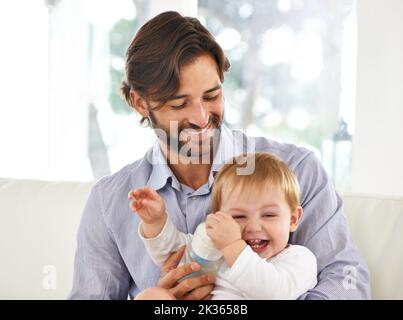 Ich liebe jede Minute zusammen. Beschnittene Ansicht eines Vaters, der seinem jungen Sohn eine Flasche gab. Stockfoto