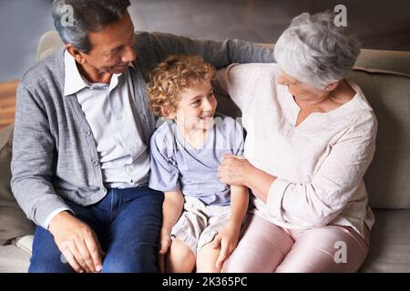 Hes hübsch wie sein Vater. Großeltern sitzen mit ihrem Enkel auf der Couch. Stockfoto