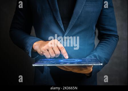 Geschäftsmann hält Tablet-Computer auf dunklem Hintergrund. Geschäftsmann nutzt moderne digitale Technologie, um Geschäfte zu verwalten. Mann in Anzug hält digitalen Tisch Stockfoto