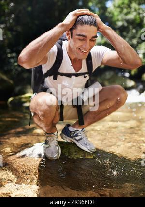 So erfrischend... Ein junger Mann, der für eine Pause beim Wandern im Wald anhält. Stockfoto