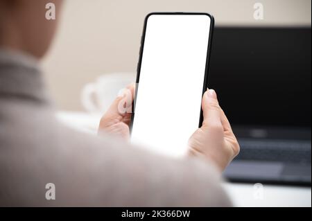 Handy-Modell. Eine kurze Aufnahme einer Geschäftsfrau, die in einem modernen Bürozimmer auf ein Smartphone mit leerem Bildschirm schaut. Frau Hand hält Handy mit leeren s Stockfoto