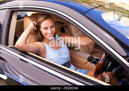 Eine Fahrt mit ihrem Sportwagen. Eine junge Frau, die in einem Sportwagen fährt. Stockfoto