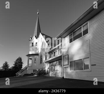 Fassade einer weißen Holzkirche bei Sonnenuntergang in der Landschaft. Lutherische Kirche in British Columbia. Foto in Schwarzweiß Stockfoto