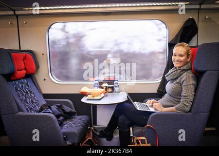 Kein besserer Weg als der Zug. Eine attraktive junge Frau, die mit dem Zug unterwegs ist. Stockfoto